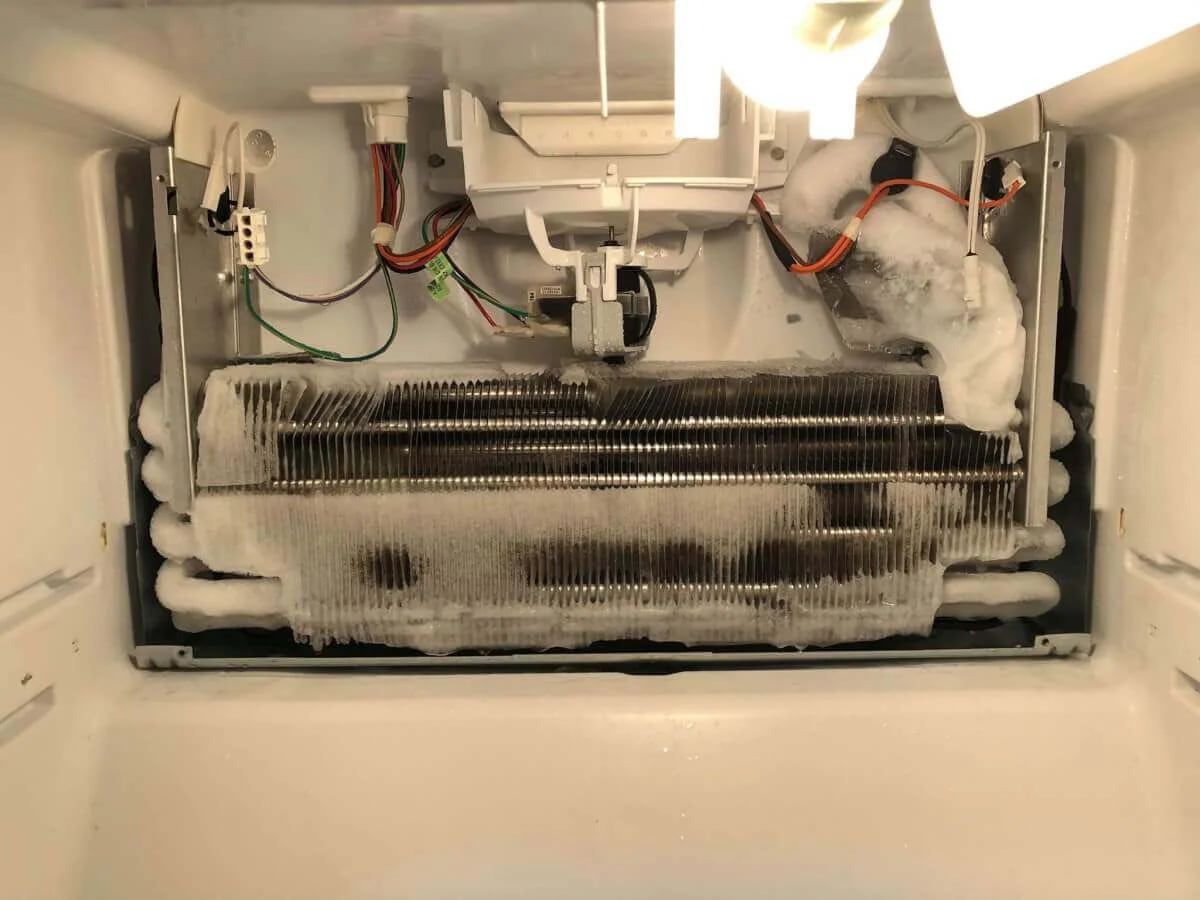 Vaporizatorul unui frigider No Frost acoperit complet de un bloc de gheață, după demontarea panoului din spate